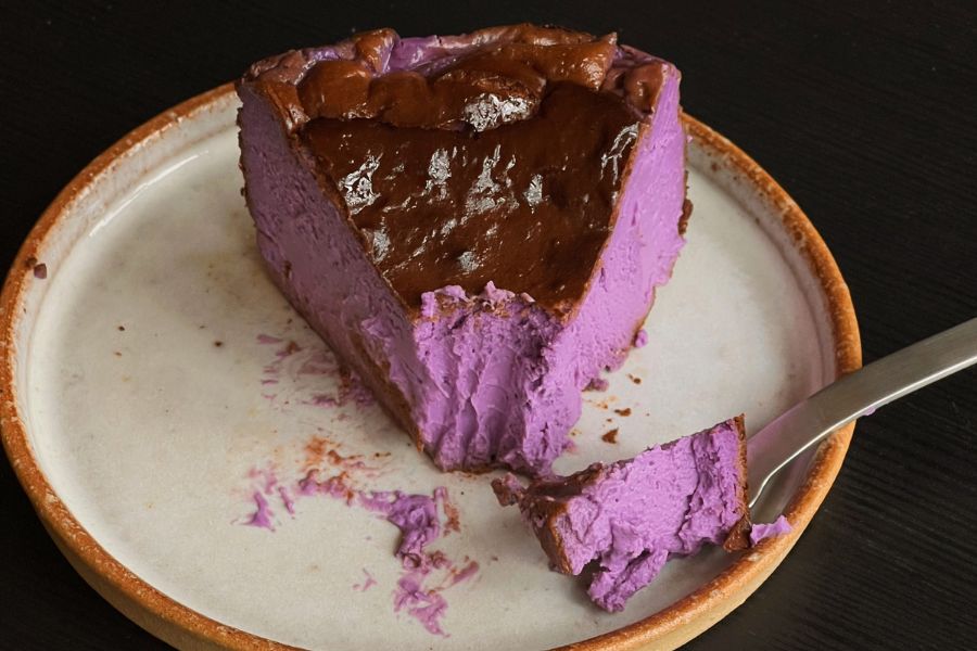 Slice of cheesecake with a bright purple filling on a white plate, Cambridge